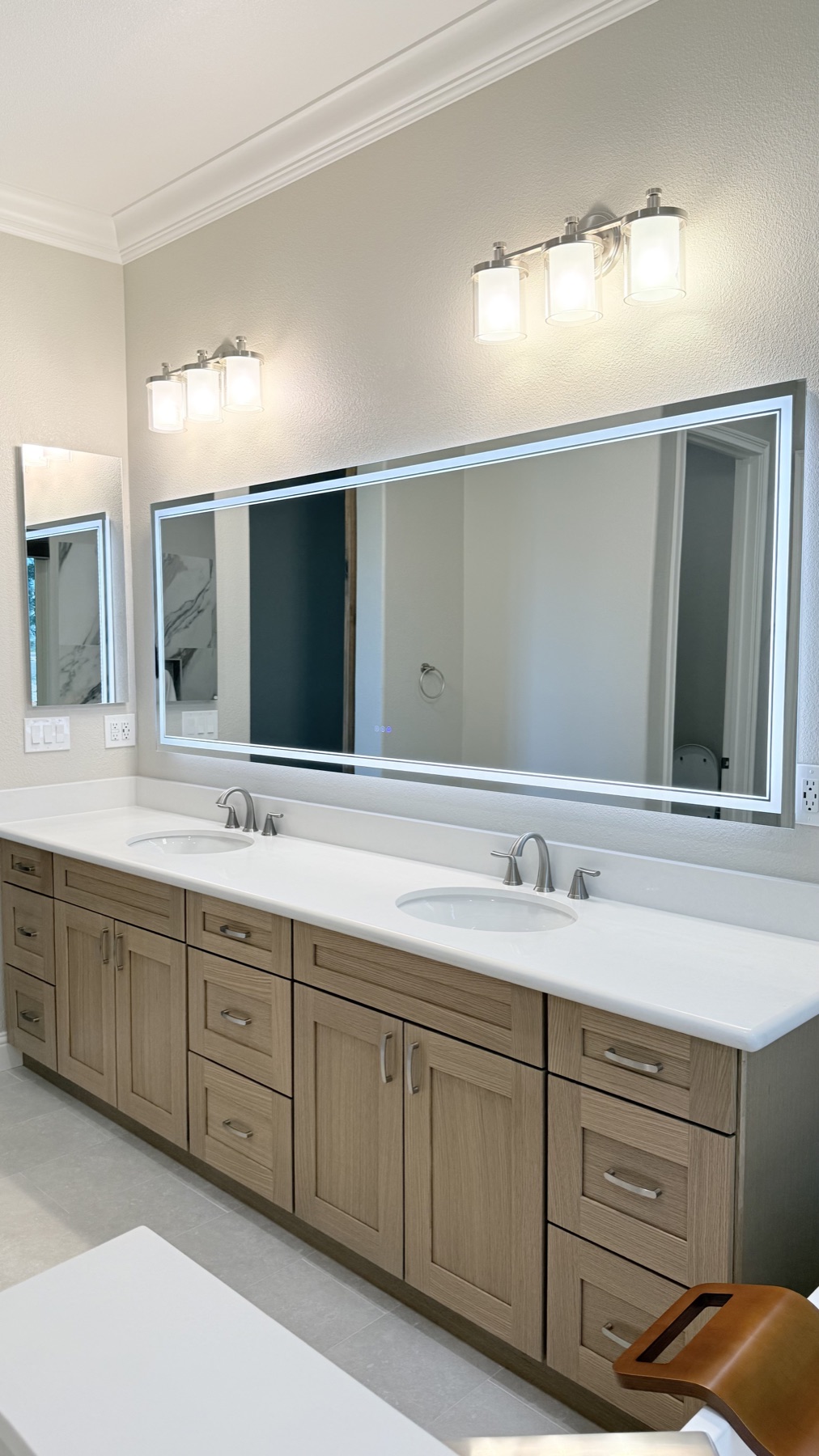 Lighted bathroom mirror above a warm wood double vanity in El Dorado Hills